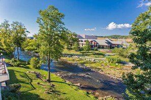 A riverside view with a building featuring a covered patio and a view of a river. - Bear Crossing 502 (Pigeon Forge)