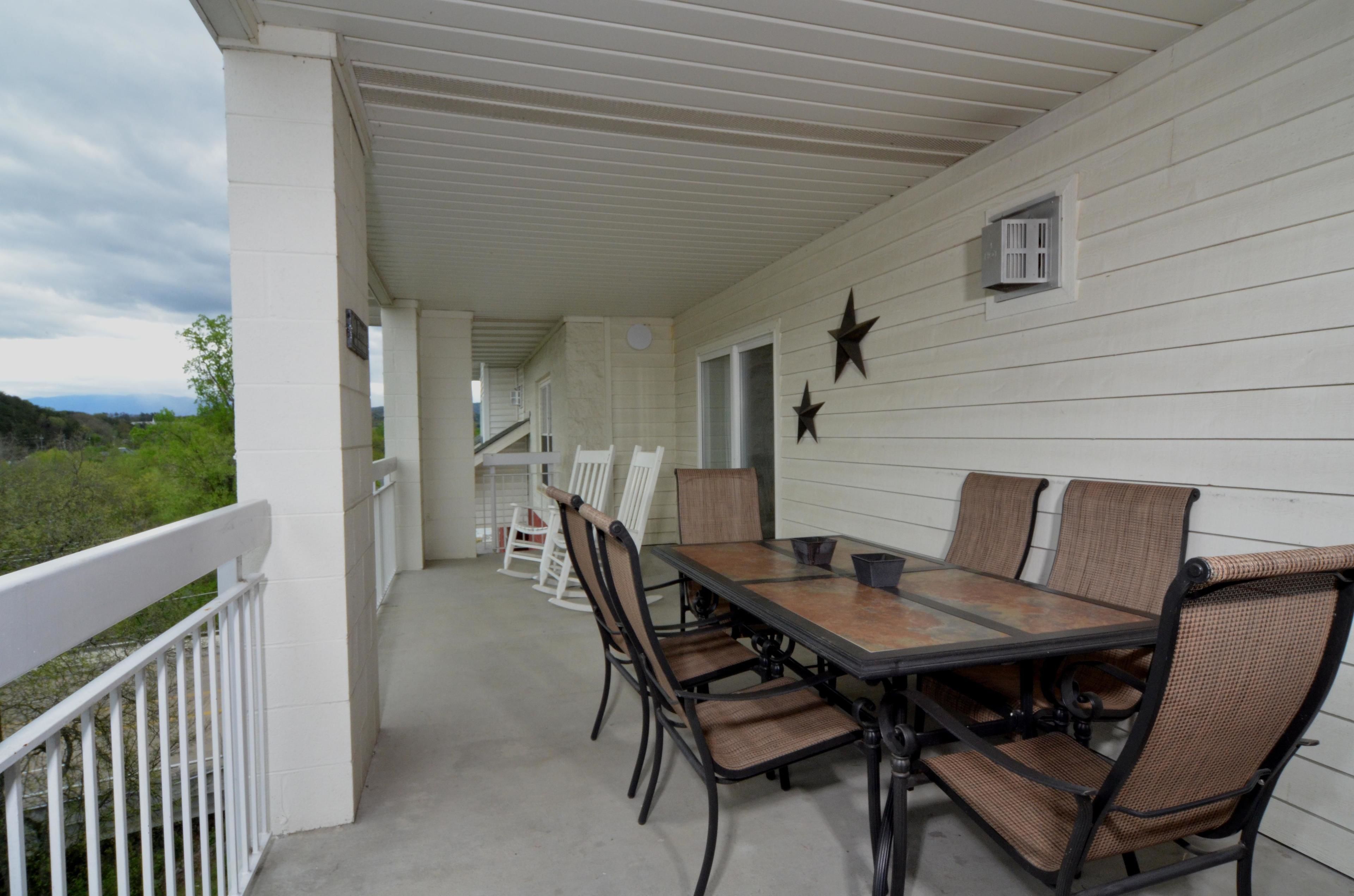 Eine überdachte Terrasse im Freien mit Esstisch und Stühlen, weißen Geländern und dekorativen Sternen an der Wand.