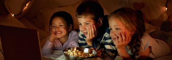 Un grupo de personas sentadas en un sofá con un cuenco de palomitas.