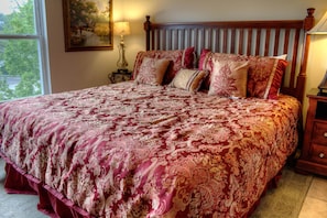 Un dormitorio con una cama grande, un cabecero de madera y una mesita de noche con lámpara.