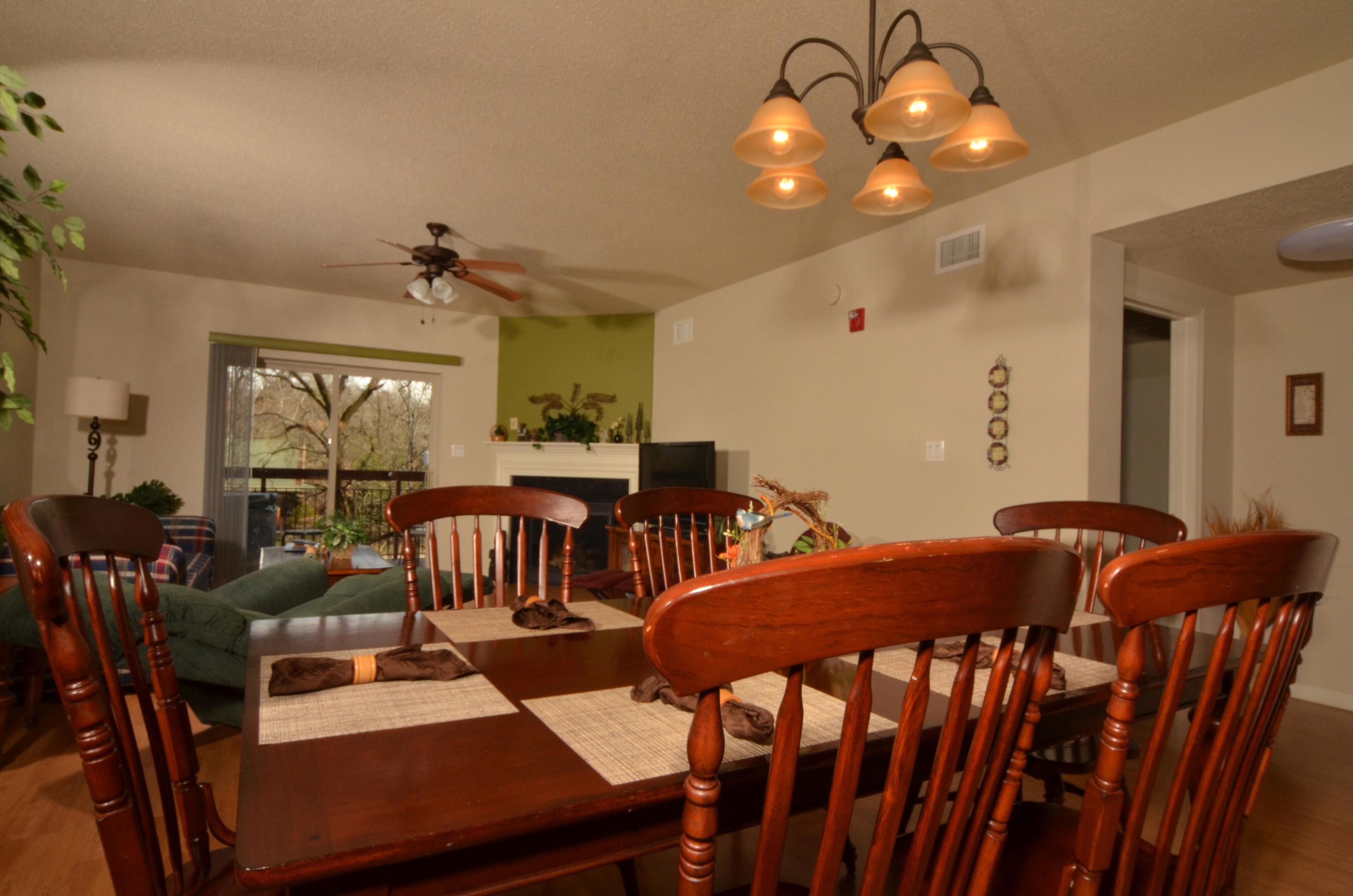 A dining area with a wooden table, chairs, and a ceiling fan.