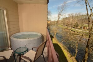 Ein Balkon mit Whirlpool, Stühlen und Blick auf einen Fluss und Bäume.