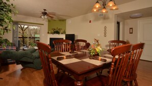 A dining room with a wooden table, six chairs, and a ceiling fan.