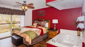 A bedroom with a bed, a nightstand, a lamp, a window, and a bathtub. - Cedar Lodge 105 (Pigeon Forge)