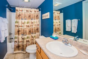 A bathroom with a shower curtain featuring animal prints, a white sink, and a mirror. - Cedar Lodge 105 (Pigeon Forge)