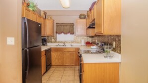 A compact kitchen with wooden cabinets, a black refrigerator, a sink, and a stove.