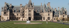 A large, historic building with a symmetrical facade, a central entrance, and a well-maintained lawn in front.