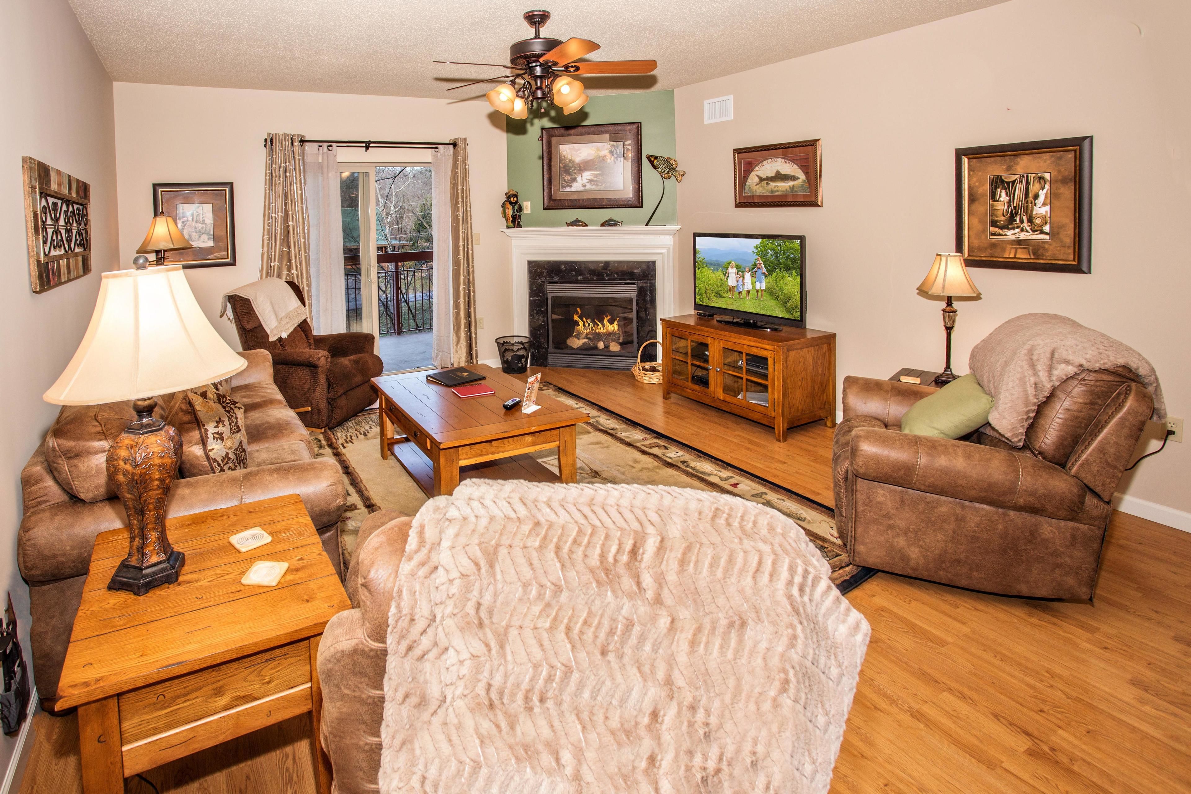 A living room with a fireplace, a television, and a ceiling fan.