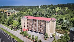A multi-story hotel with a red roof, surrounded by greenery and a parking lot. - Cedar Lodge 402 (Pigeon Forge)