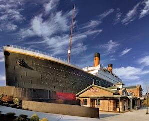 Ein großes Kreuzfahrtschiff liegt im Hafen fest, im Vordergrund ein Gebäude mit der Aufschrift 'White Star'.