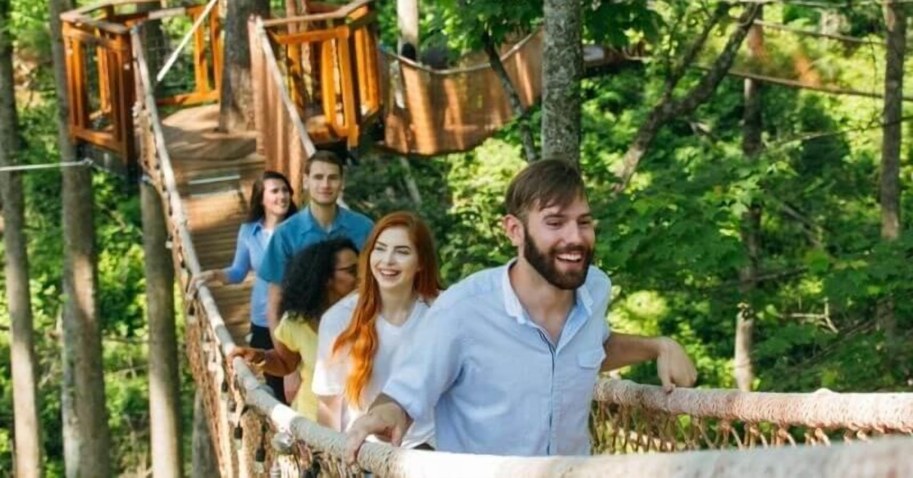 Un groupe de personnes se trouve sur un pont en bois, dans une zone boisée.