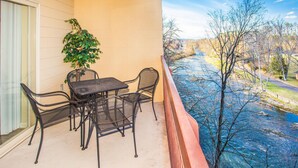 Ein Balkon mit Tisch und Stühlen, einem Blumentopf und Blick auf einen Fluss.