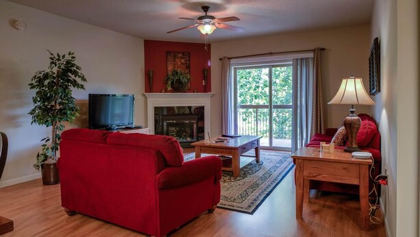 A living room with a red sofa, a wooden coffee table, a fireplace, and a television. - Cedar Lodge 405 (Pigeon Forge)