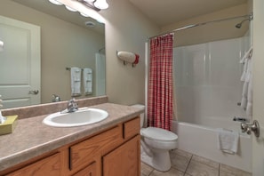 A bathroom with a sink, mirror, toilet, and shower. - Cedar Lodge 701 (Pigeon Forge)