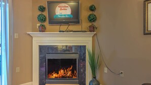 A living room with a fireplace, a television mounted above it, and a potted plant beside the fireplace. - Cedar Lodge 701 (Pigeon Forge)