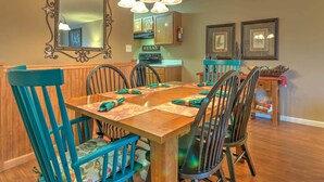 A dining area with a wooden table, teal chairs, and a large mirror above. - Cedar Lodge 701 (Pigeon Forge)