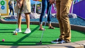 Ein Minigolfplatz mit grüner Kunstrasen, einem Putting-Green und einer Steinbordurierung.