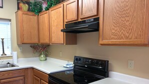A kitchen with wooden cabinets, a black stove, and a white countertop.