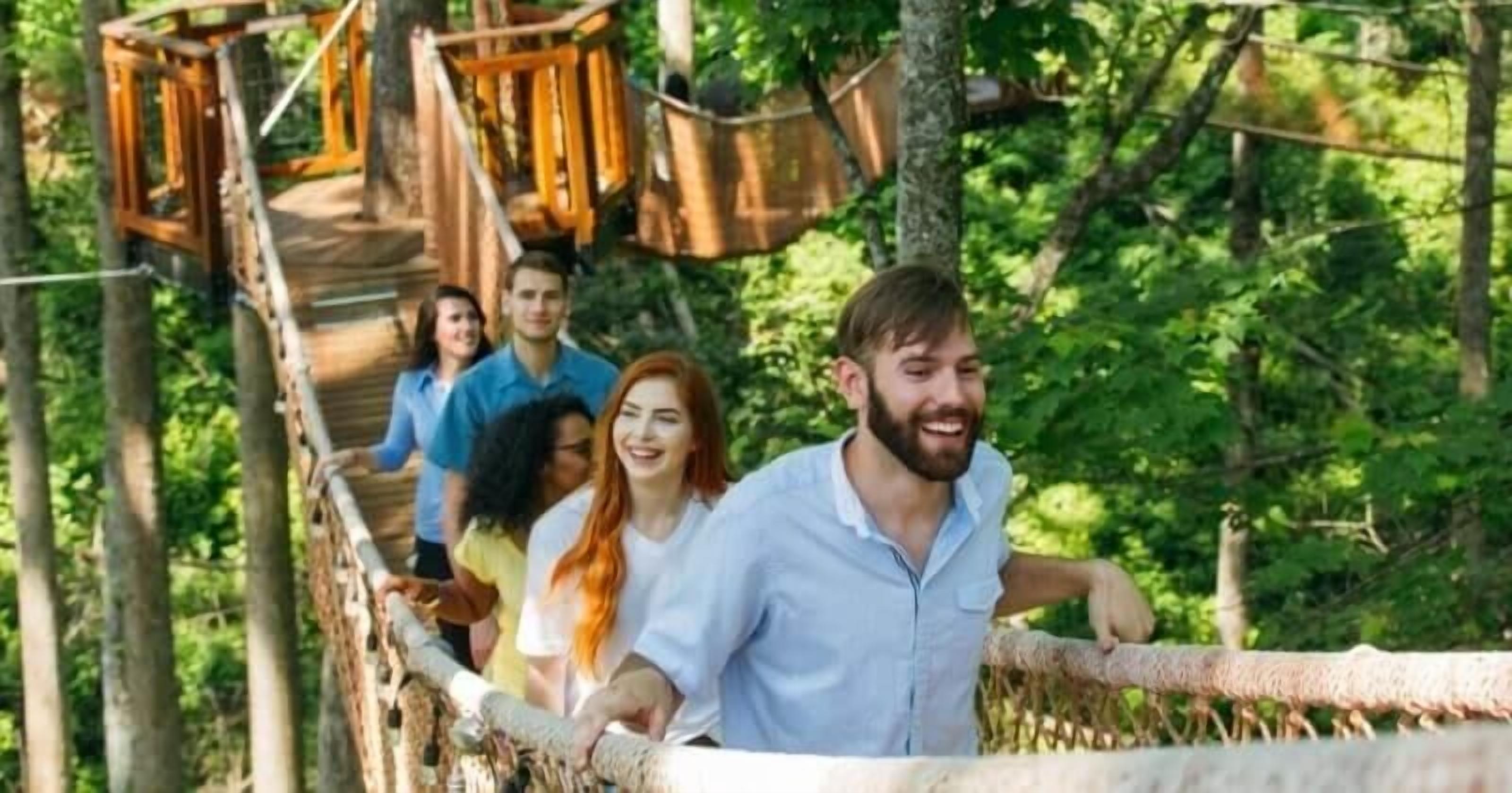 Eine Gruppe von Menschen auf einer Holzbrücke in einem bewaldeten Gebiet.