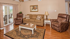 A living room with a ceiling fan, a sofa, two armchairs, a coffee table, and a patterned rug. - Whispering Pines 102hc (Pigeon Forge)