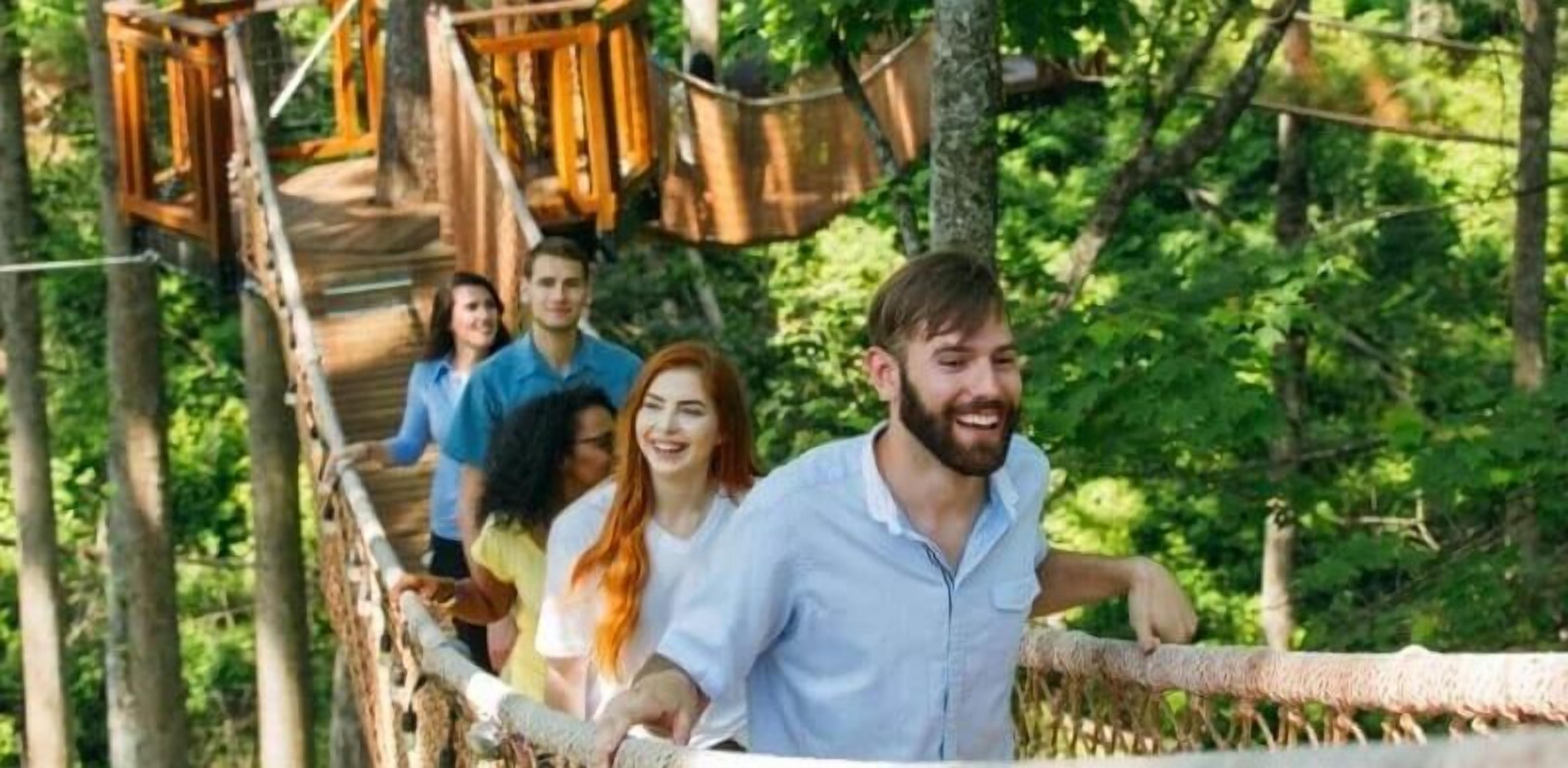 Eine Gruppe von Menschen auf einer Holzbrücke in einem bewaldeten Gebiet.