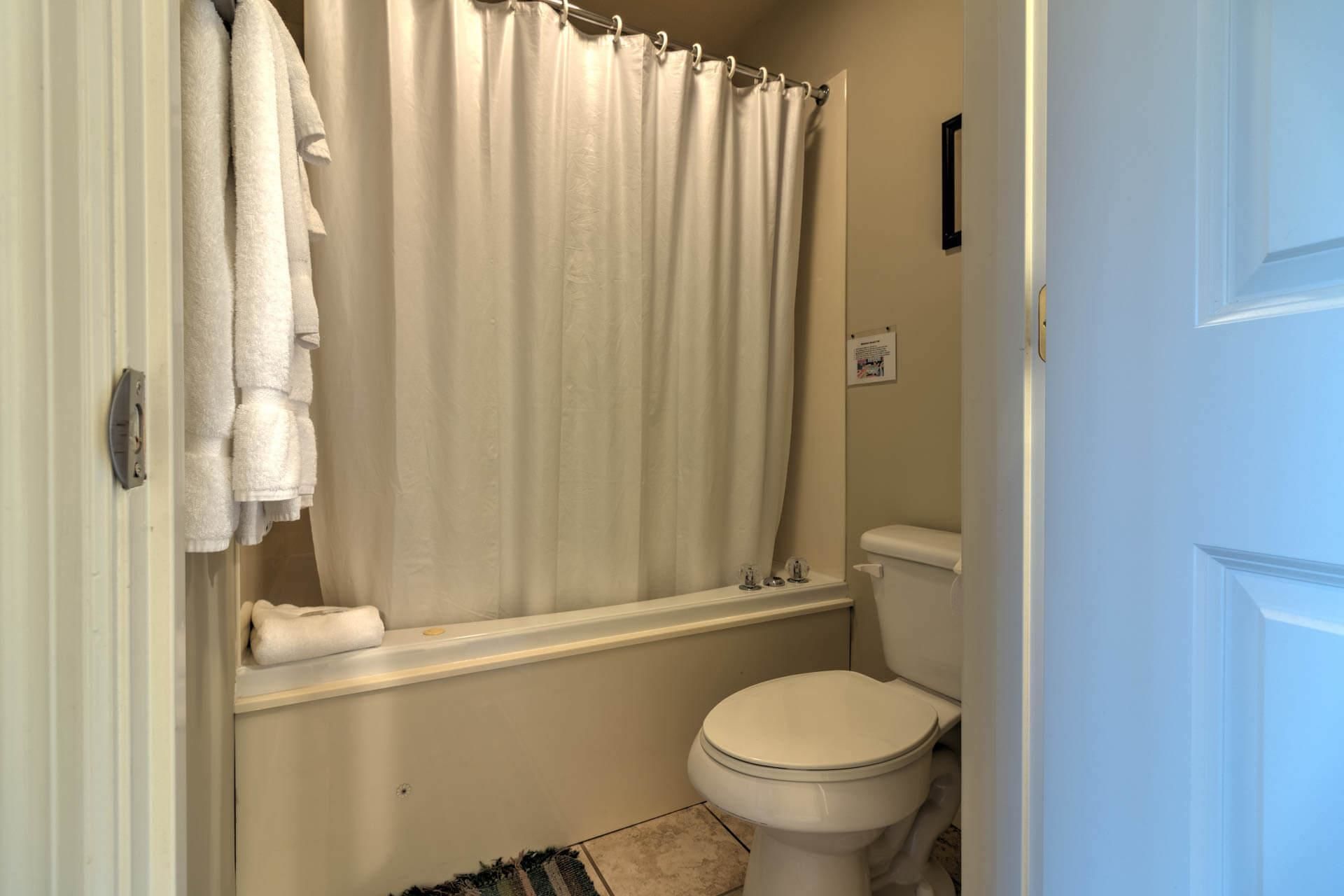 Un bagno con il water, una vasca da bagno con tenda da doccia e un porta asciugamani.