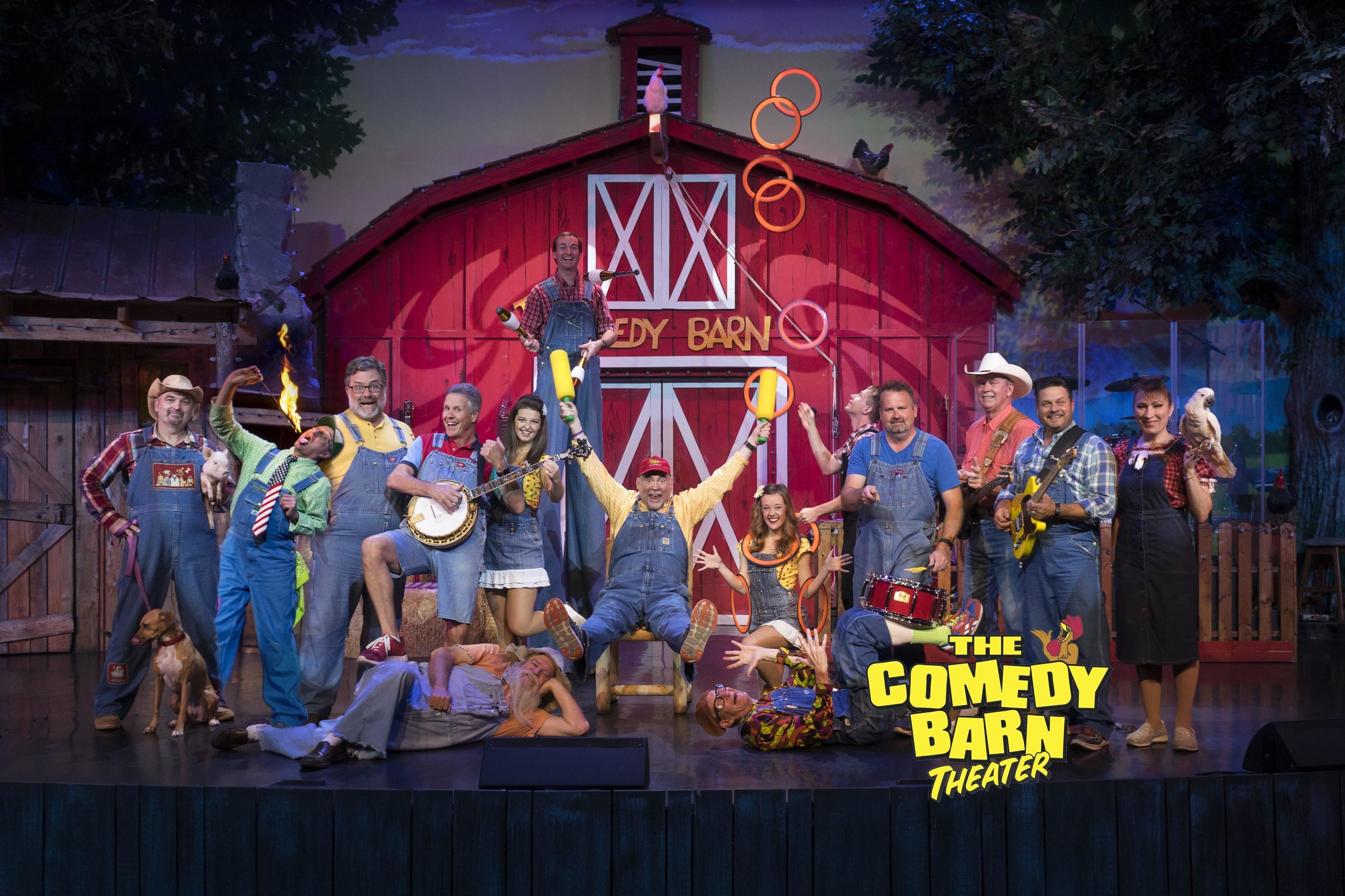 A group of people on a stage with a barn backdrop, indicating a theatrical setting.