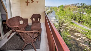 A balcony with wicker furniture and a view of a river and greenery. - Cedar Lodge 603 (Pigeon Forge)