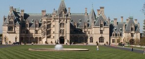 Un grand bâtiment historique à la façade symétrique, doté de nombreuses cheminées et d’une cour intérieure avec une fontaine.