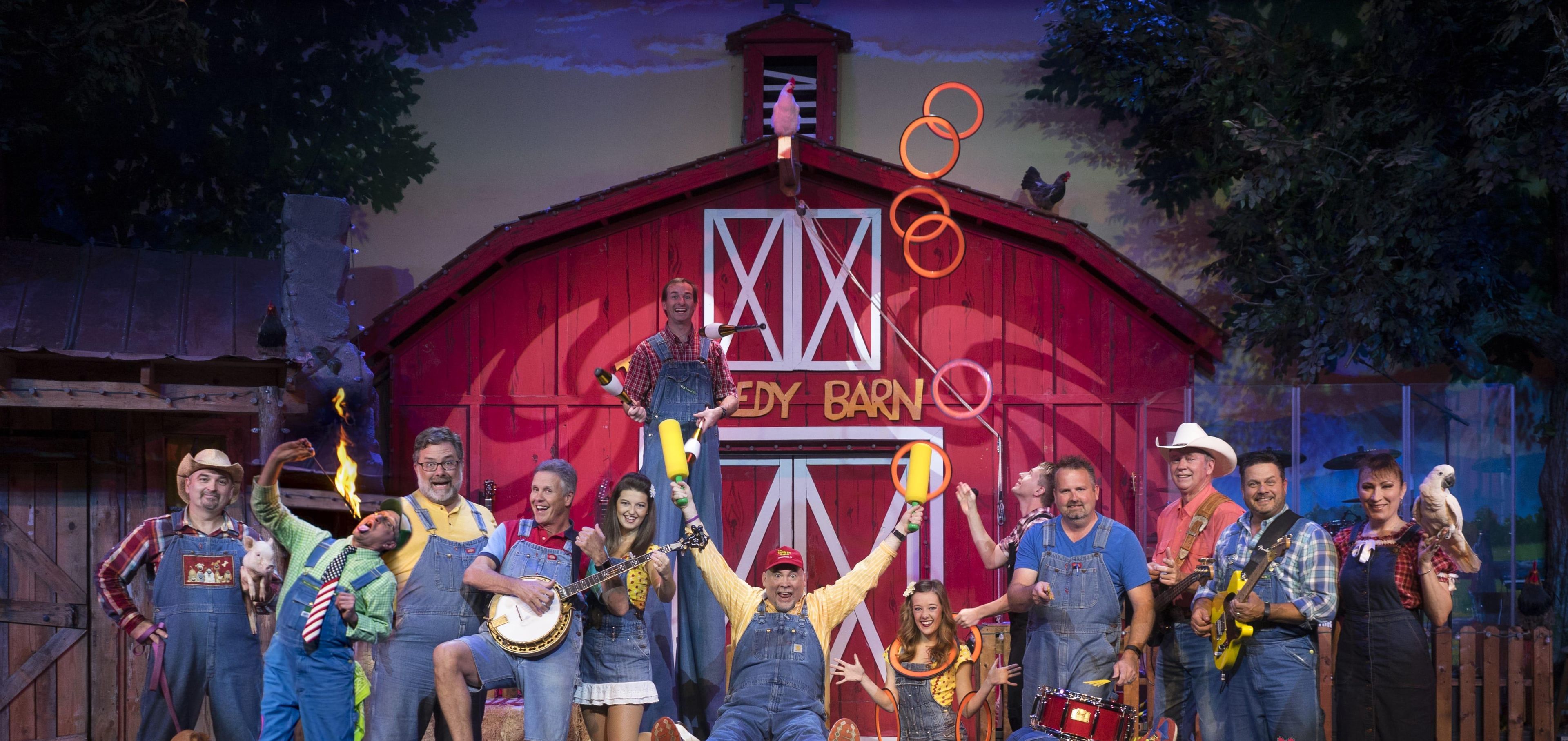 A group of people performing on a stage with a barn backdrop.