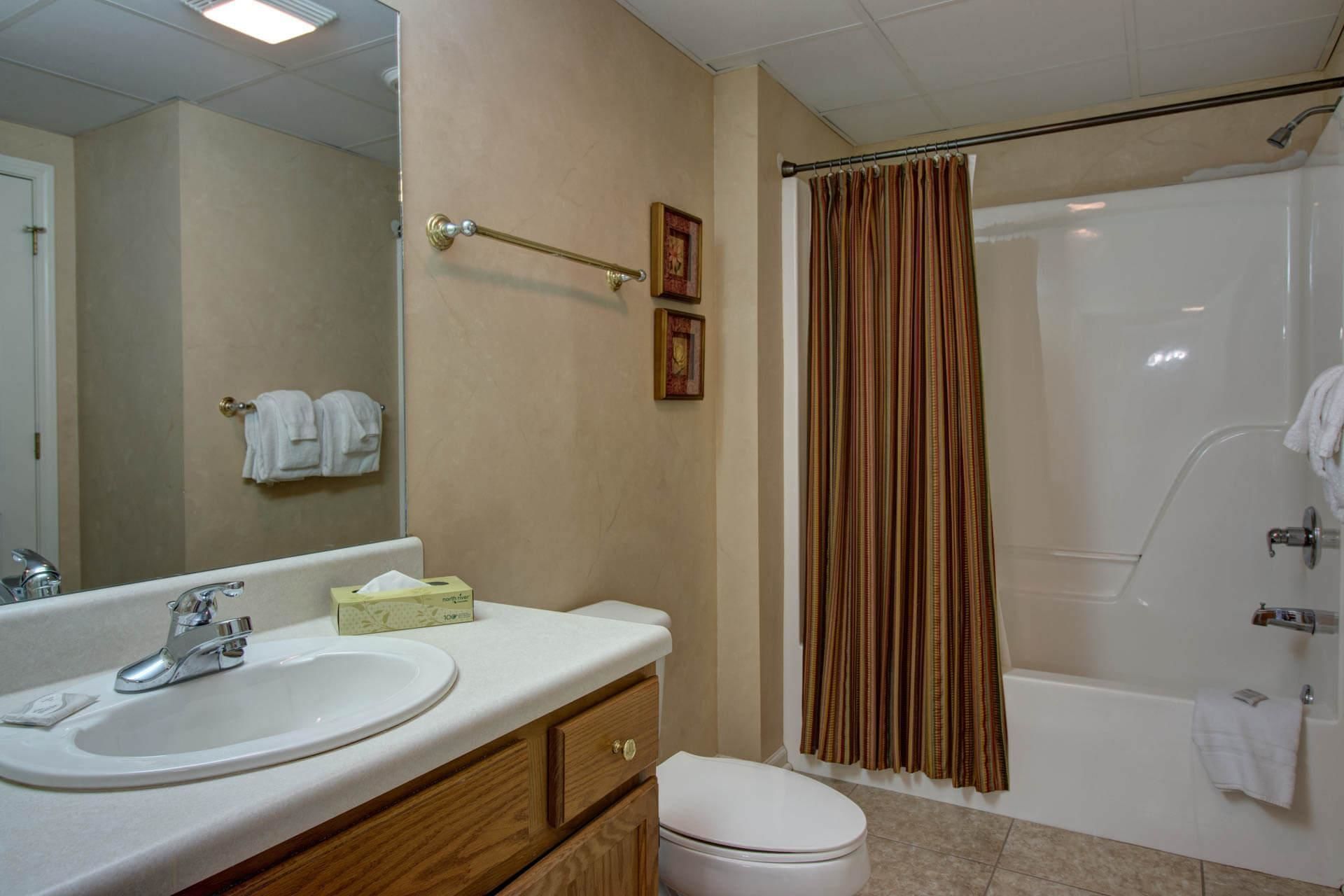 A bathroom with a sink, mirror, toilet, and shower.