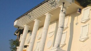 Ein Gebäude mit klassischer Architektur, das Säulen und einen Balkon mit der Aufschrift 'WONDERVORIES' zeigt.