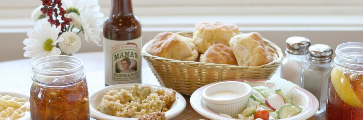 Une table sur laquelle on trouve divers aliments, notamment des biscuits, une bouteille de miel de la marque Mama's Farmhouse et un bocal de cornichons.