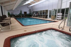 Een binnenzwembad met ligbedden, een whirlpool en een muurschildering.