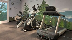 Un gimnasio con bicicletas estáticas, una elíptica y una cinta de correr.