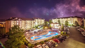 A hotel with multiple buildings, a swimming pool, and a parking lot. - Whispering Pines 222 (Pigeon Forge)