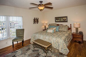 A bedroom with a bed, a chair, a bench, a ceiling fan, and two bedside tables with lamps. - Whispering Pines 104 (Pigeon Forge)