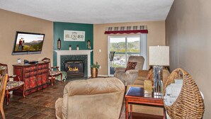 Una sala de estar con chimenea, televisor y vistas al exterior.