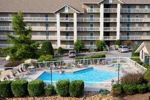 A hotel with a swimming pool, multiple balconies, and a parking area. - Whispering Pines 214 (Pigeon Forge)
