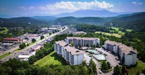 A hotel with multiple buildings, a swimming pool, and a parking lot. - Whispering Pines 214 (Pigeon Forge)