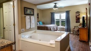 A spacious bathroom with a large bathtub, a shower area, and a vanity with a countertop. - Whispering Pines 232 (Pigeon Forge)