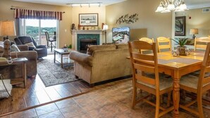 A living room with a fireplace, a dining table with chairs, and a sofa. - Whispering Pines 232 (Pigeon Forge)