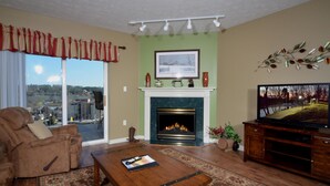 A living room with a fireplace, a sofa, a coffee table, and a television. - Whispering Pines 232 (Pigeon Forge)