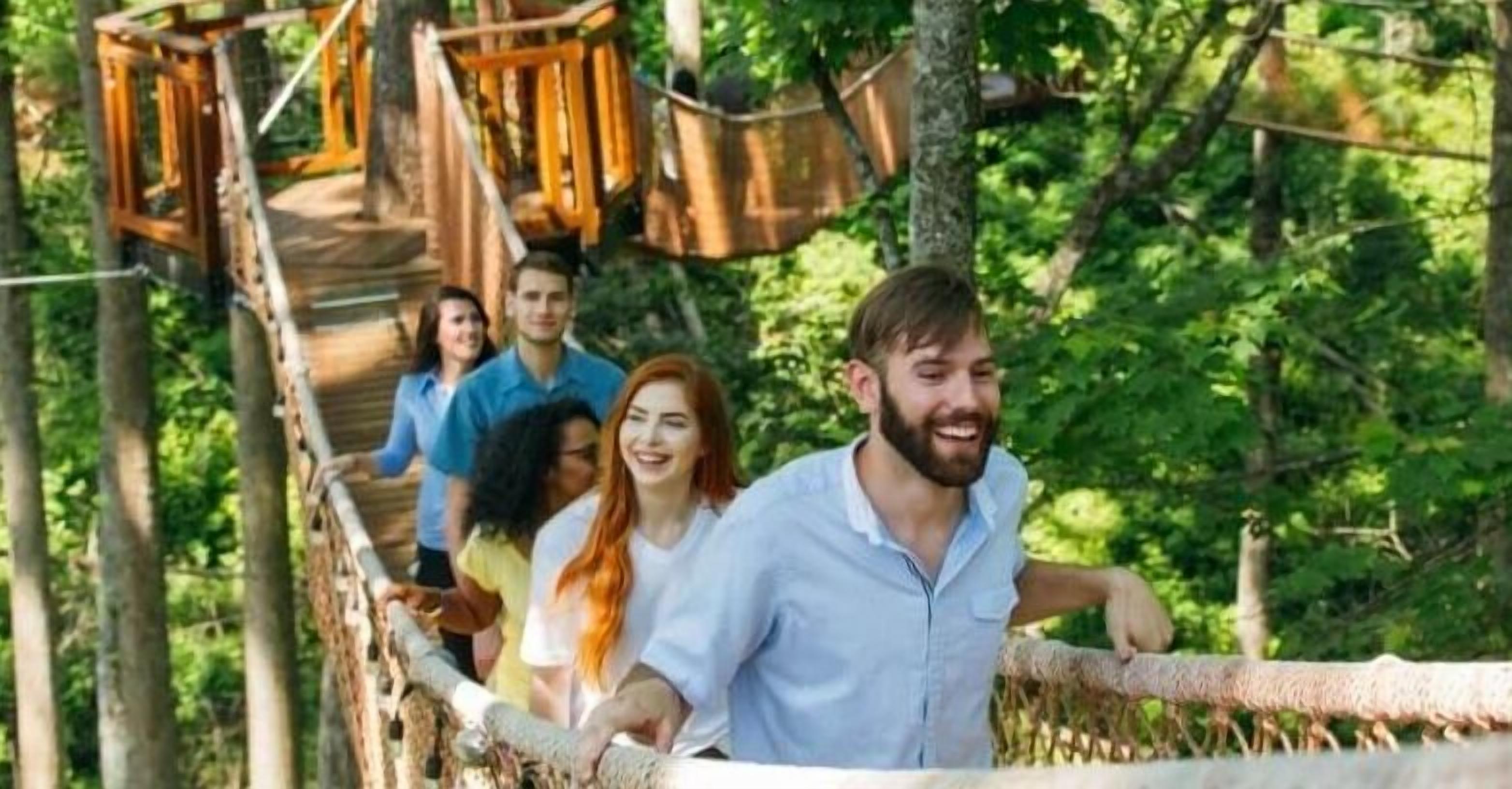 Eine Gruppe von Menschen auf einer Holzbrücke in einem bewaldeten Gebiet.