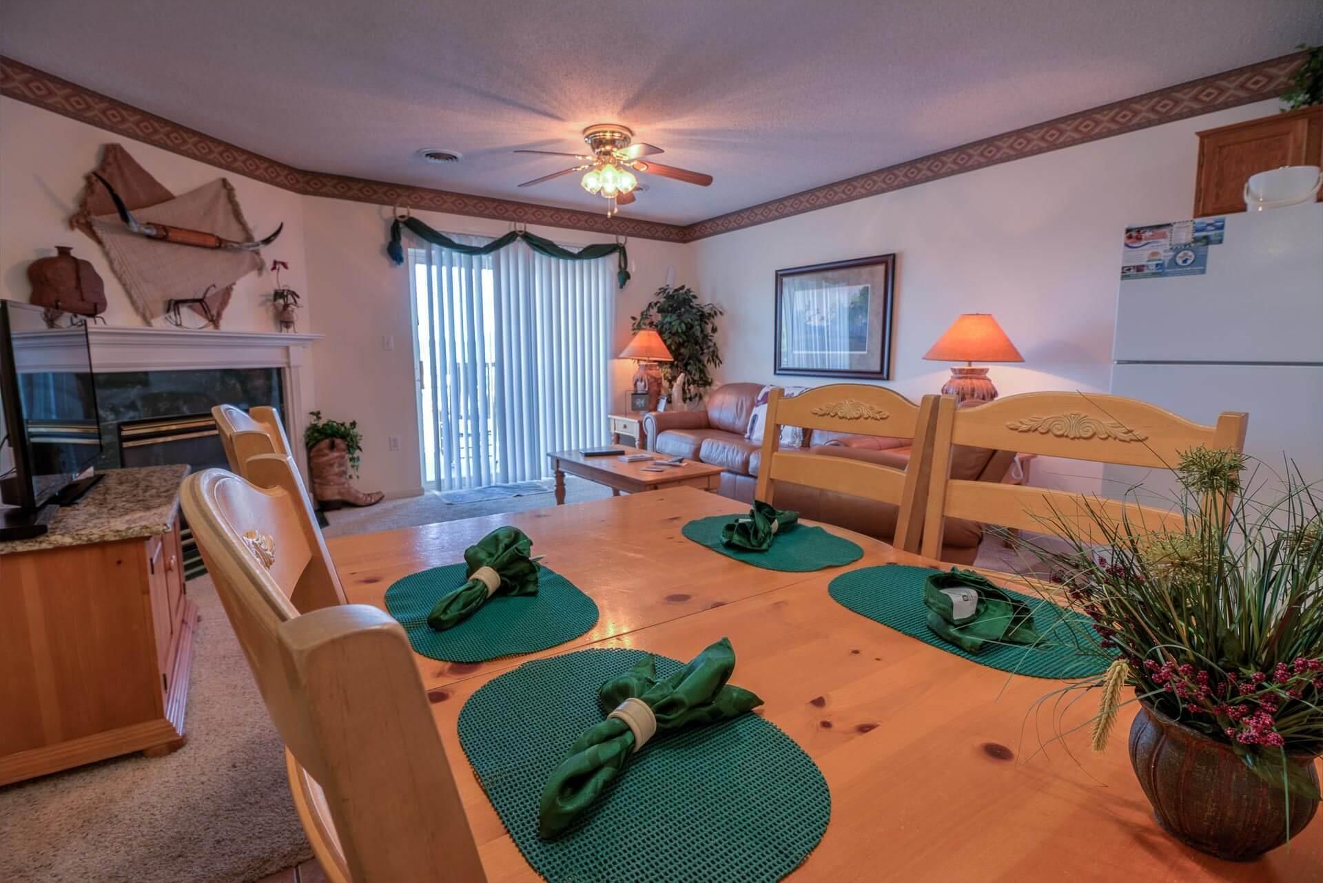 Een gezellige woonkamer met een houten eettafel, stoelen, een bank en een plafondventilator.