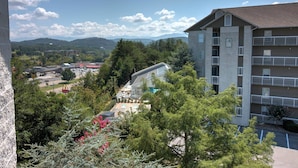 Ein mehrstöckiges Gebäude mit Balkonen, umgeben von Bäumen und blauem Himmel.