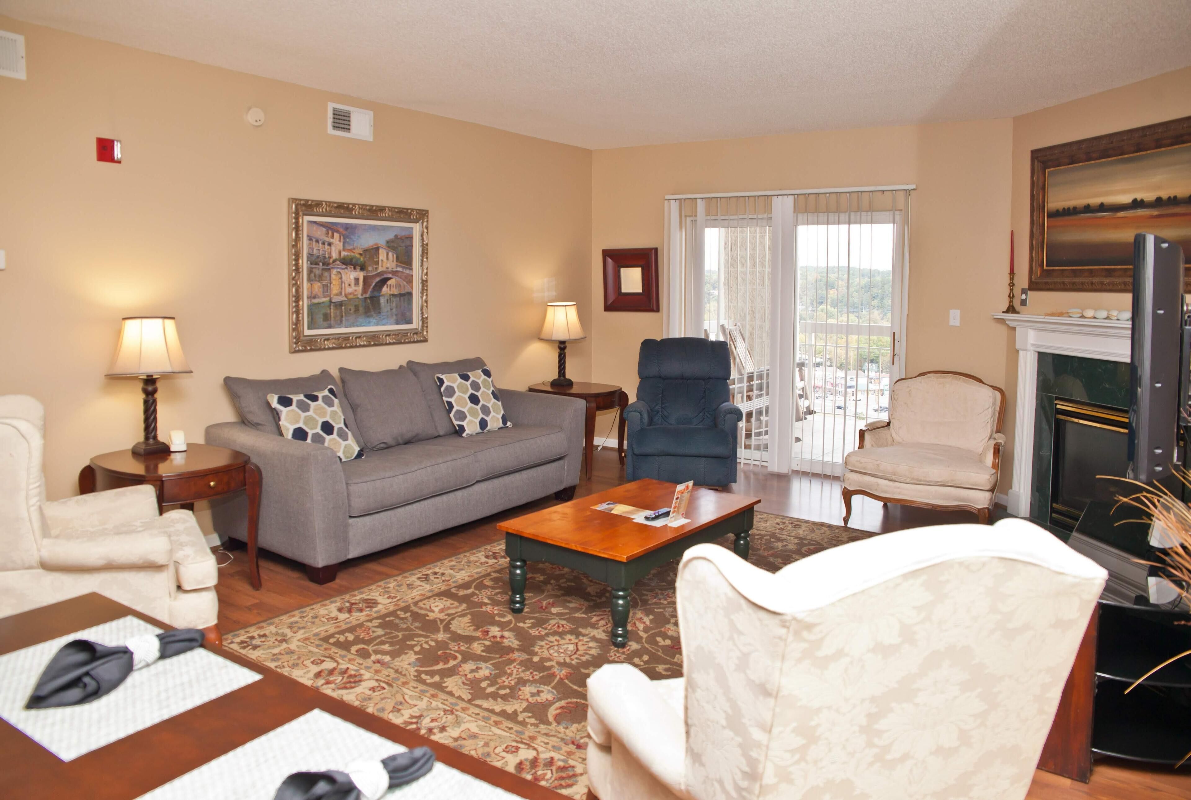 A living room with a sofa, armchairs, a coffee table, and a fireplace.