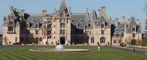 Un grand bâtiment historique à la façade symétrique, doté de nombreuses cheminées et d’une entrée centrale.