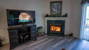 A living room with a fireplace, a television, and a bear statue. - Whispering Pines 243 (Pigeon Forge)