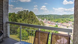 A balcony with wicker chairs, a view of a town with buildings and trees, and a clear sky. - Whispering Pines 243 (Pigeon Forge)